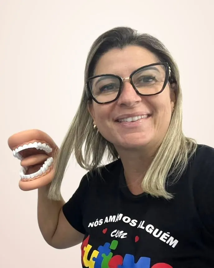 Patrícia Lima sorrindo, com o modelo de boca que usa no atendimento de fonoaudiologia